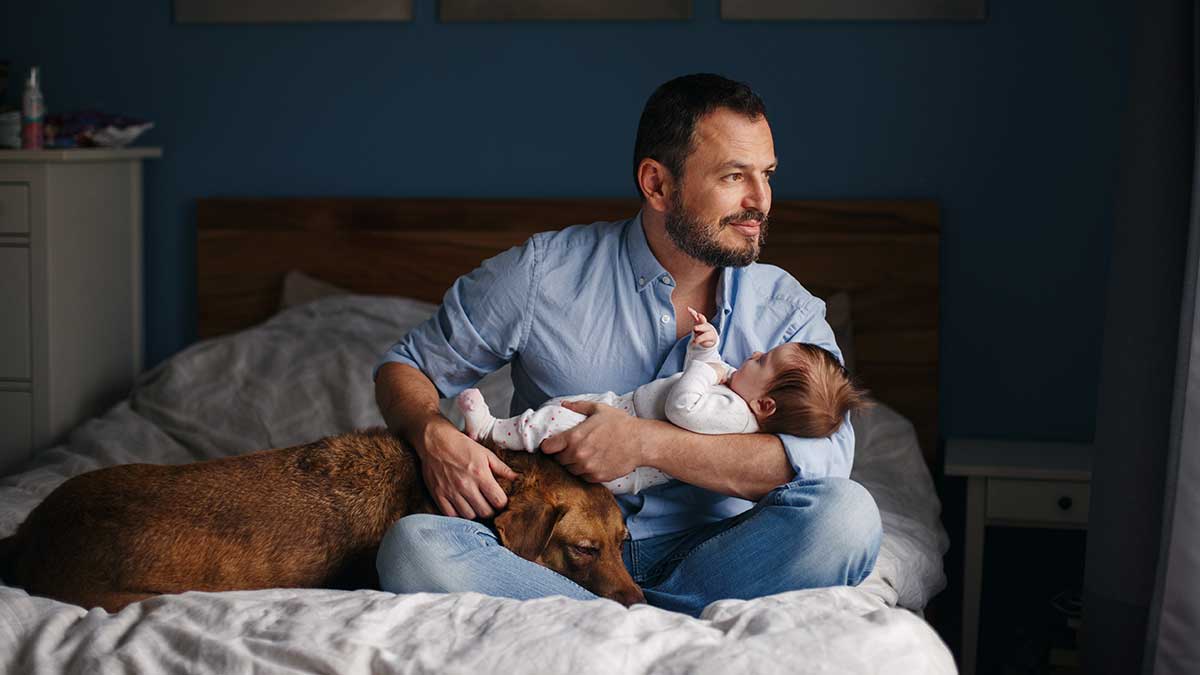 A man sitting with his baby and dog